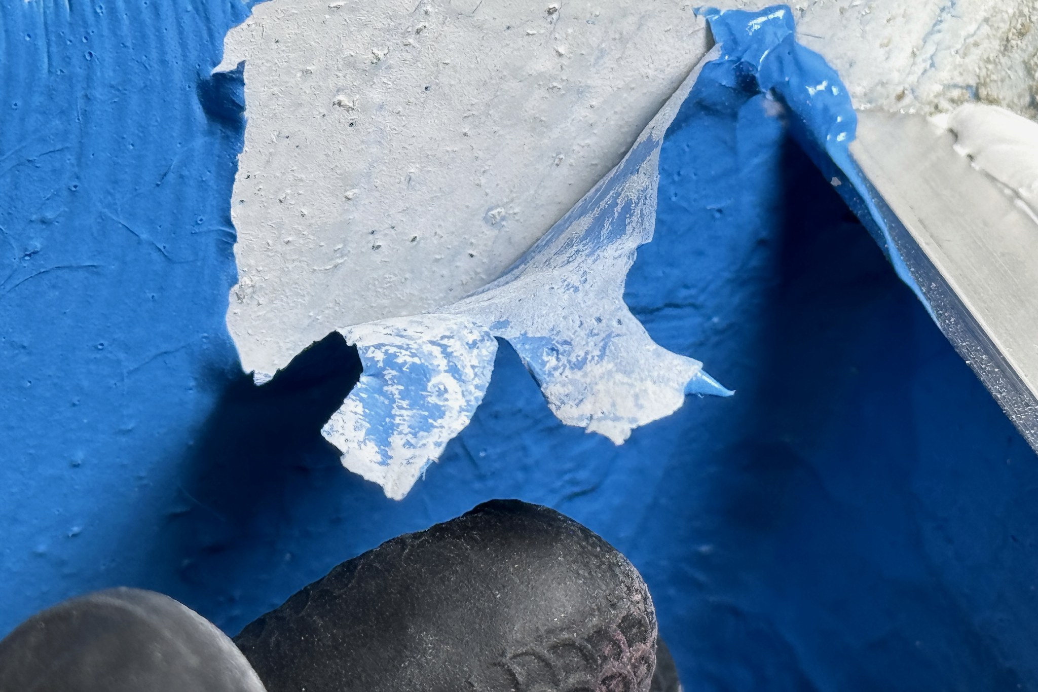 A bond breaker torn and lifting away from the internal corner of a waterproofing membrane