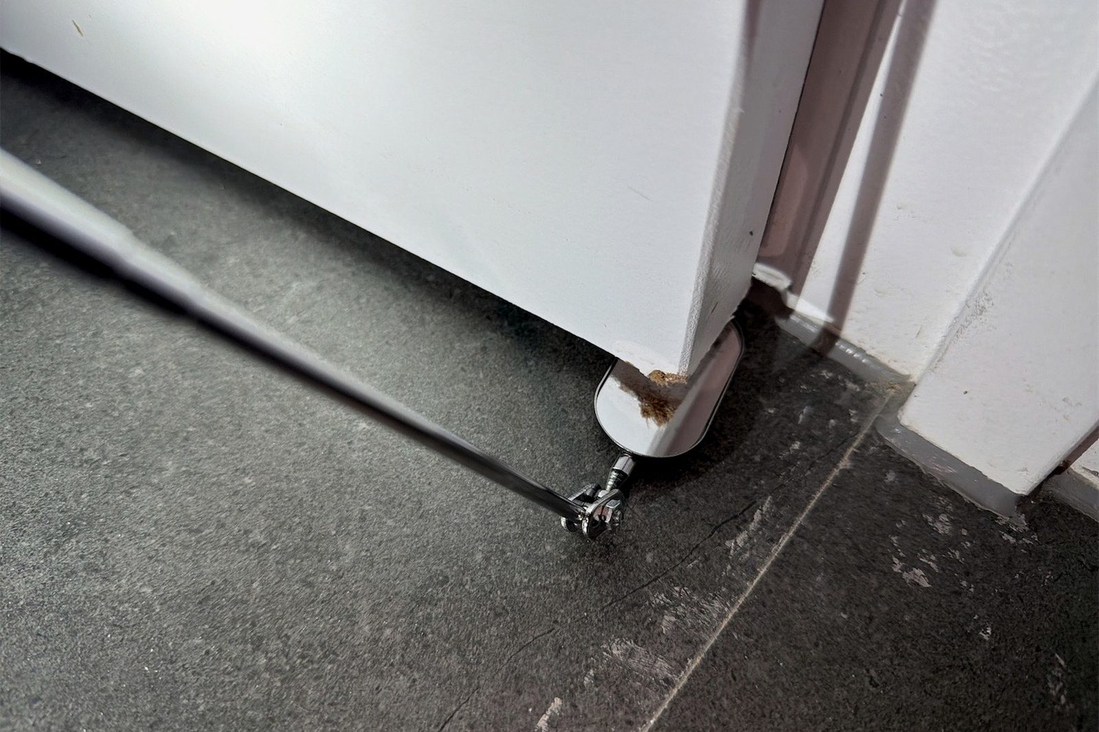 The base of an internal door frame meeting the floor, with a failed fixing and a visible gap