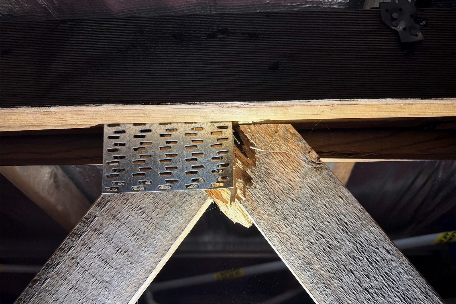 A roof truss joint where the timber has split away at the nail plate connection