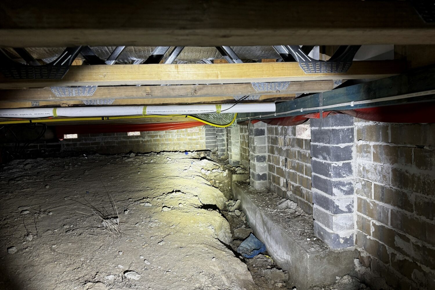 A subfloor space showing brick piers and dwarf walls carrying timber bearers and floor joists