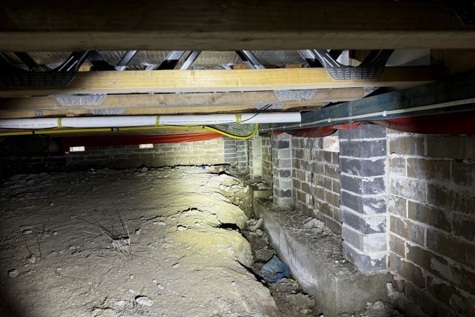 A subfloor space showing brick piers and dwarf walls carrying timber bearers and floor joists