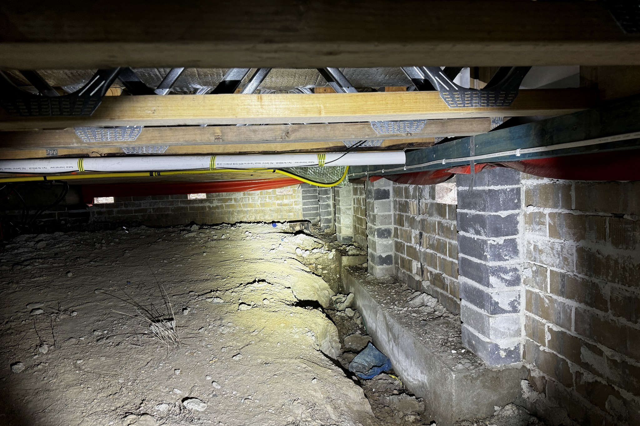A subfloor space showing brick piers and dwarf walls carrying timber bearers and floor joists