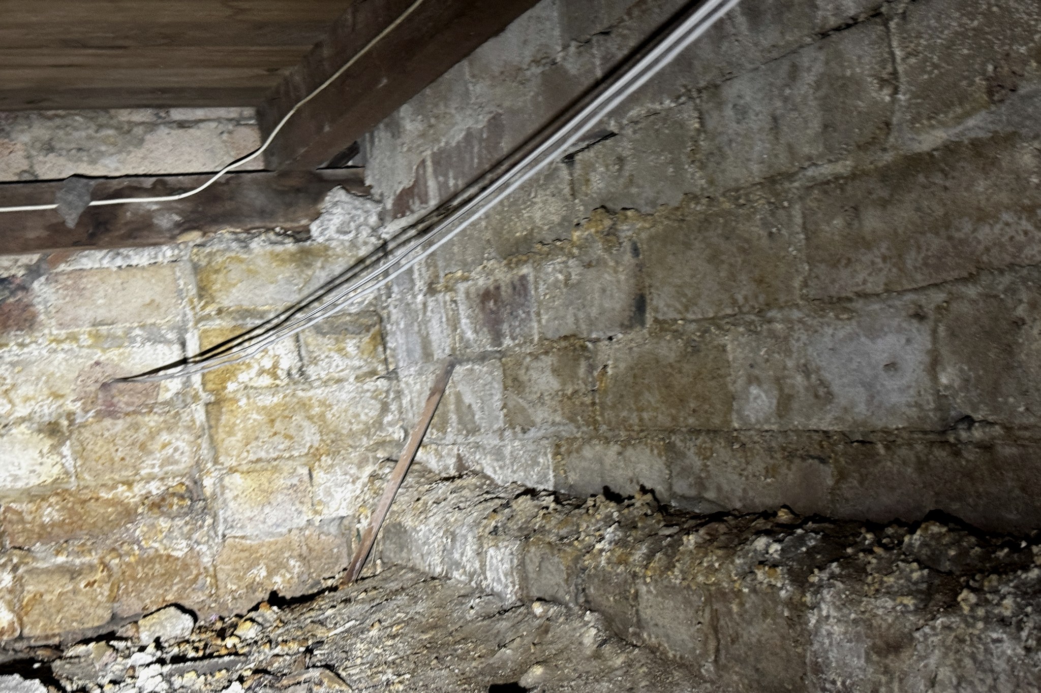 Deteriorated structural brickwork in a subfloor with a timber bearer bearing directly on it