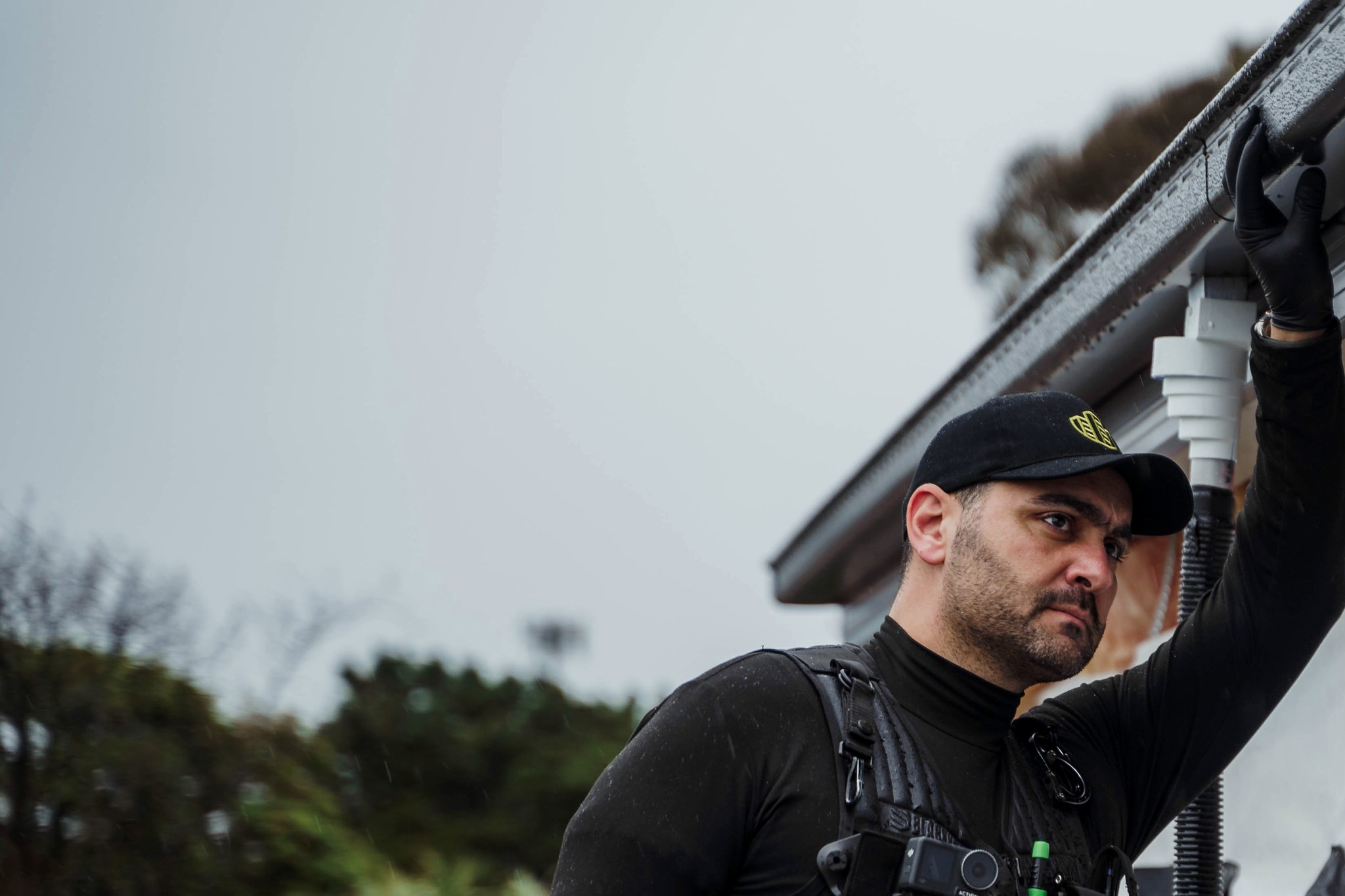 A Site Inspections building consultant inspecting the eaves and gutter line of a partly built house in the rain