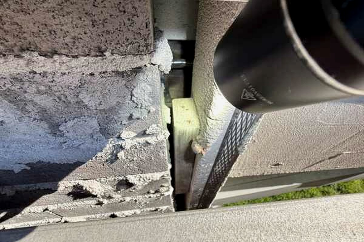 Gap between blockwork and the wall frame beside a downpipe, with framing member and fixing exposed to the exterior